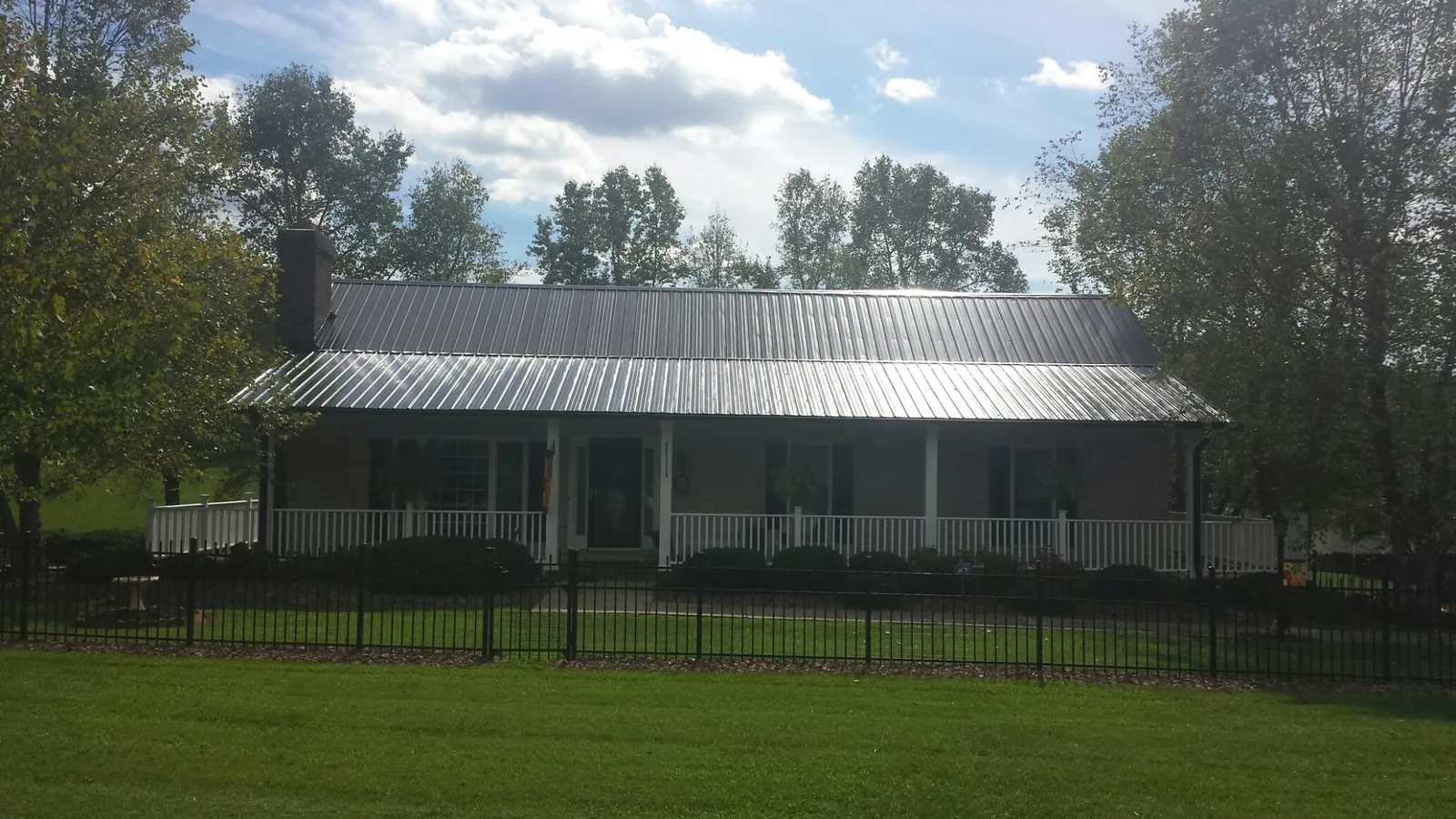 Gray metal roof on a brick ranch with a full width front porch — Gutter Guard Installation work by our crew in Davenport